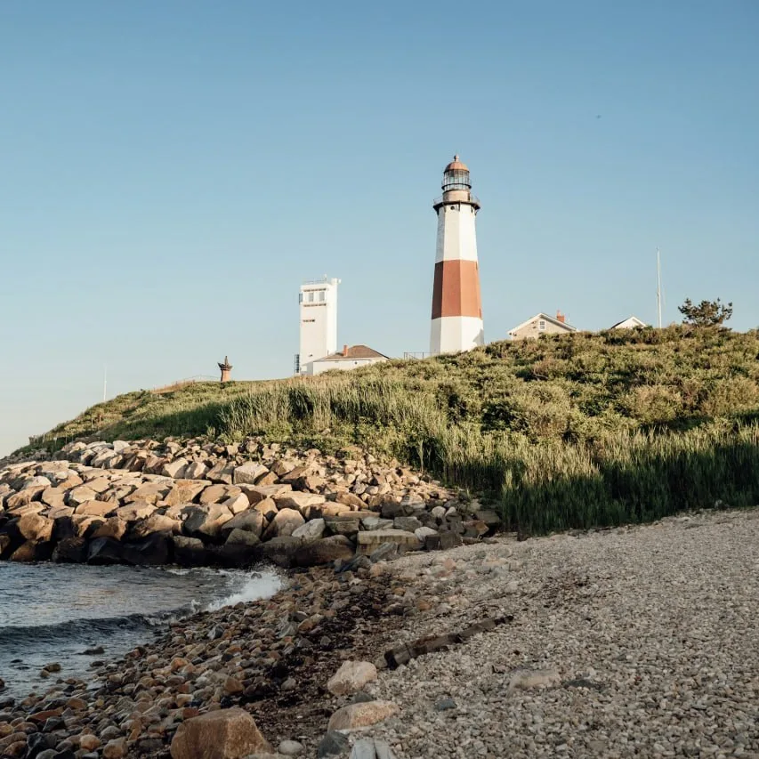 Montauk Point Lighthouse above a rocky shoreline and the ocean.