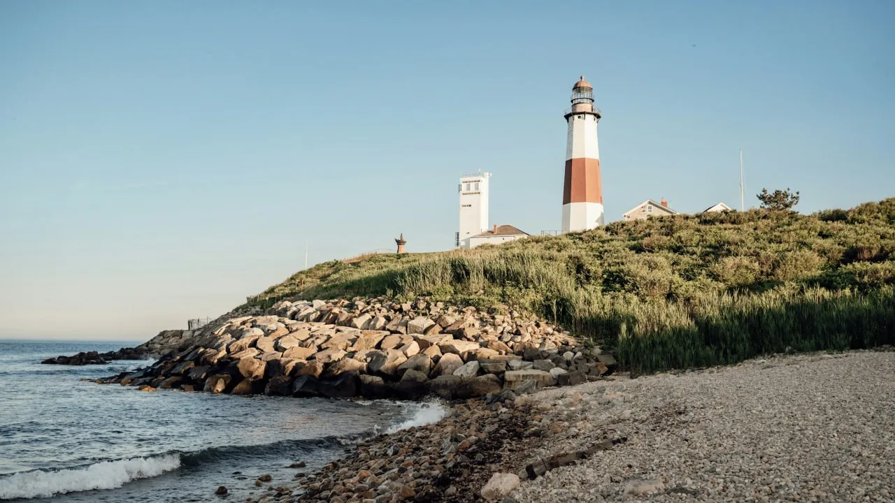 Montauk Point Lighthouse above a rocky shoreline and the ocean.